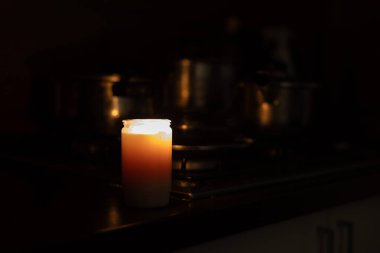 Mutfakta, ocağın yanında tabakları olan yanan bir mum. Ukrayna 'daki savaş nedeniyle elektrik kesintisi