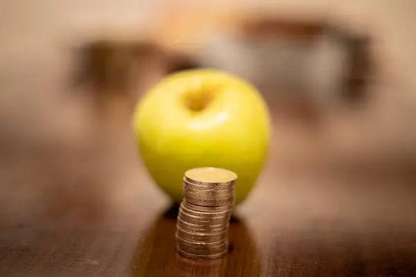 stock image Apple and a stack of coins. Rising prices due to the war in Ukraine