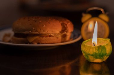 Cooking by candlelight. Hamburger on a plate and a candle.  No electricity due to war in Ukraine clipart