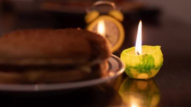 Mum ışığında yemek pişirmek. Tabakta hamburger ve mum. Ukrayna 'da savaş nedeniyle elektrik yok