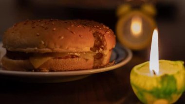 Mum ışığında yemek pişirmek. Tabakta hamburger ve mum. Ukrayna 'da savaş nedeniyle elektrik yok