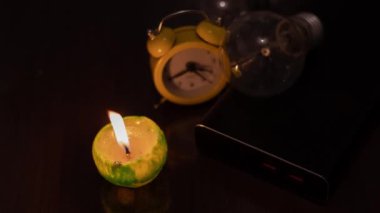 Yanan mum, ampul, elektrik bankası ve saat. Ukrayna 'daki savaştan kaynaklanan kalıcı elektrik kesintileri