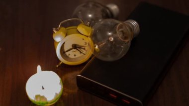 Yanan mum, ampul, elektrik bankası ve saat. Ukrayna 'daki savaştan kaynaklanan kalıcı elektrik kesintileri