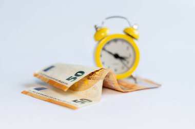 Alarm saati ve beyaz arkaplandaki banknotlar