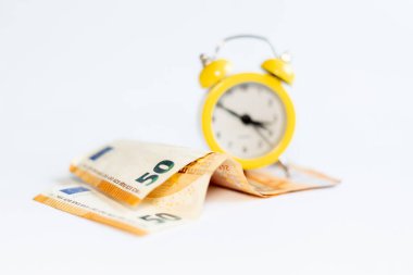 Alarm saati ve beyaz arkaplandaki banknotlar