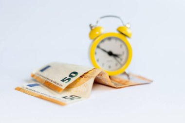 Alarm saati ve beyaz arkaplandaki banknotlar