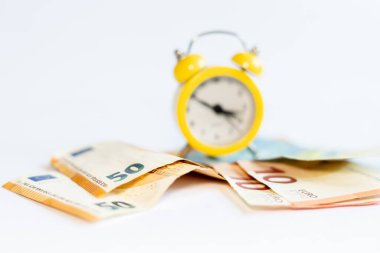 Alarm saati ve beyaz arkaplandaki banknotlar