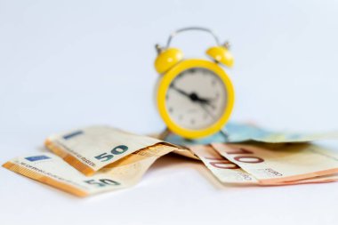Alarm saati ve beyaz arkaplandaki banknotlar