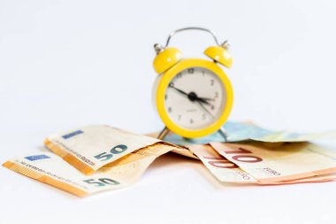 Alarm saati ve beyaz arkaplandaki banknotlar