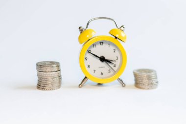 Beyaz arkaplanda alarm saati ve bozuk paralar