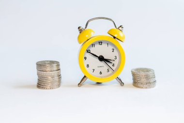 Beyaz arkaplanda alarm saati ve bozuk paralar