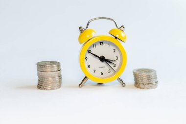 Beyaz arkaplanda alarm saati ve bozuk paralar