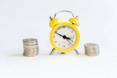 Beyaz arkaplanda alarm saati ve bozuk paralar