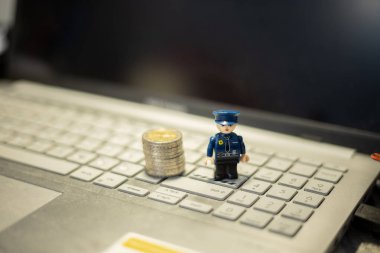 Oyuncak polis ve bozuk paralar dizüstü bilgisayarda. İnternet üzerinden mali işlemlerin korunması