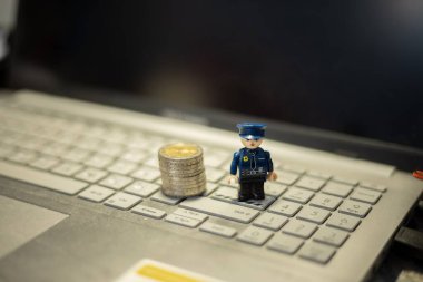 Oyuncak polis ve bozuk paralar dizüstü bilgisayarda. İnternet üzerinden mali işlemlerin korunması
