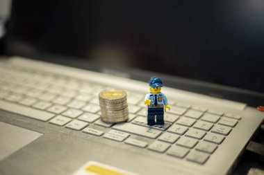 Oyuncak polis ve bozuk paralar dizüstü bilgisayarda. İnternet üzerinden mali işlemlerin korunması
