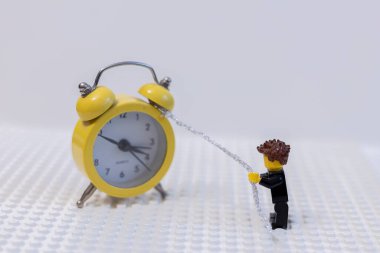 LEGO adamı saati zincirle çeker. Zaman yönetimi kavramı.