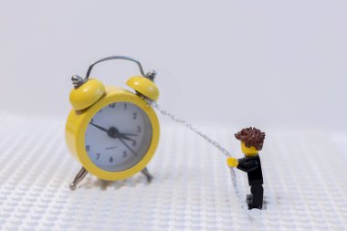 LEGO adamı saati zincirle çeker. Zaman yönetimi kavramı.