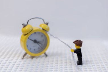 LEGO adamı saati zincirle çeker. Zaman yönetimi kavramı.