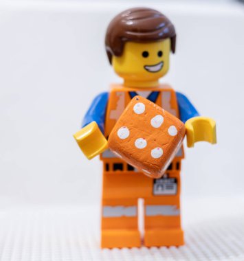 LEGO çalışanı, yüzünde neşeli bir ifadeyle, bir zar Lego Filmi 2 Emmet 'i tutuyor.