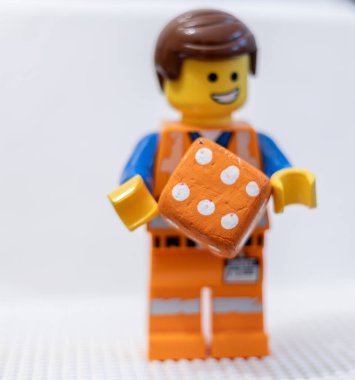 LEGO çalışanı, yüzünde neşeli bir ifadeyle, bir zar Lego Filmi 2 Emmet 'i tutuyor.