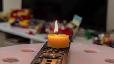 TV kumandasında yanan mum. Ukrayna 'da savaş nedeniyle elektrik kesintisi