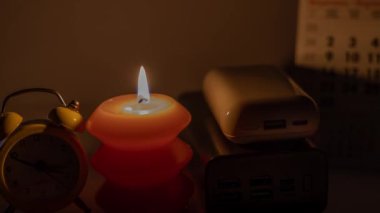 Mekanik saat ve takvimin yanında yanan mum ve güç bankaları. Ukrayna 'daki savaş nedeniyle planlanmış elektrik kesintisi