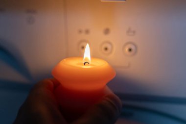 Karanlıkta çamaşır makinesinin yanında yanan mum. Ukrayna 'da savaş nedeniyle elektrik kesintisi