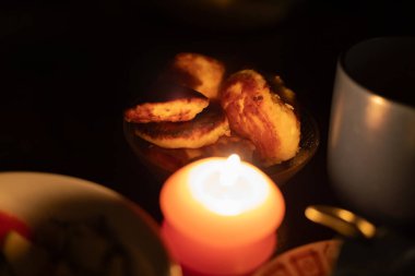 Yemeklerin arasında yanan bir mum. Ukrayna 'daki savaş nedeniyle elektrik kesintisi nedeniyle akşam yemeği.