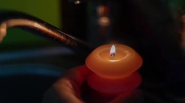 Karanlıkta mutfakta musluğun yanında yanan bir mum. Ukrayna 'da savaş nedeniyle elektrik kesintisi