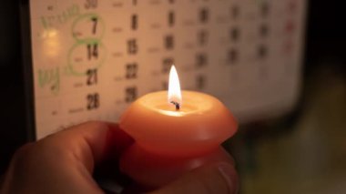 Takvimin yanında yanan mum. Ukrayna 'daki savaş nedeniyle planlanmış elektrik kesintisi