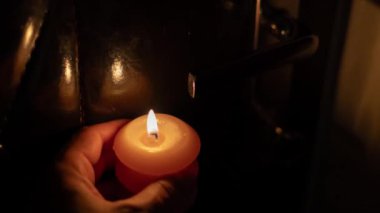 Karanlığın içinde elinde yanan bir mum. Ukrayna 'da savaş nedeniyle elektrik kesintisi