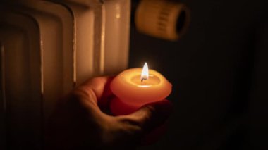 Isıtma bataryasının yanında yanan mum. Ukrayna 'da savaş nedeniyle ısı sorunları