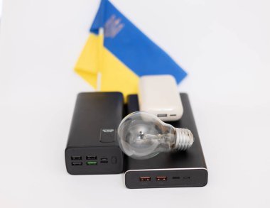 Güç bankaları ve Ukrayna bayrağına karşı çalışmayan bir ampul. Ukrayna 'daki savaş nedeniyle elektrik kesintileri