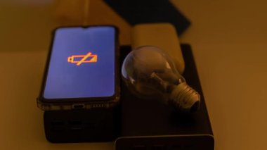Güç bankaları, boşaltılmış bir telefon ve Ukrayna bayrağına karşı çalışmayan bir ampul. Ukrayna 'daki savaş nedeniyle elektrik kesintileri