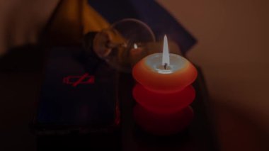Elektrik bankalarının yanında yanan bir mum, boşaltılmış bir telefon ve Ukrayna bayrağının arka planında kırık bir ampul. Ukrayna 'daki savaş nedeniyle elektrik kesintileri