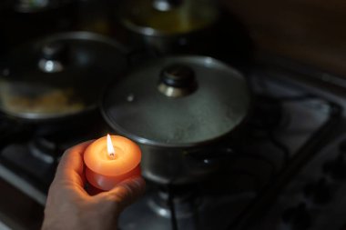 Gaz sobasının yanında yanan mum. Ukrayna 'daki savaş yüzünden karanlıkta yemek pişirmek