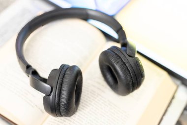 Bilgisayarın yanında açık bir kitaptaki kulaklıklar.