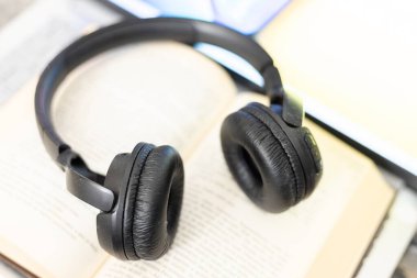 Bilgisayarın yanında açık bir kitaptaki kulaklıklar.