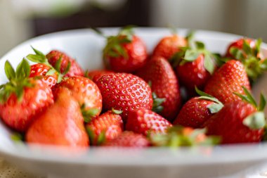 Masadaki beyaz tabakta taze çilekler.