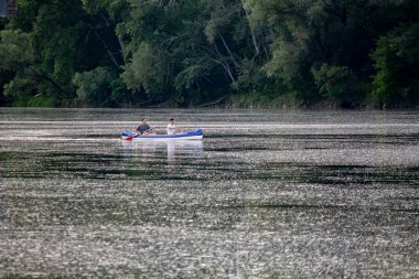 İnsanlar nehir boyunca bir teknede yelken açıyor.