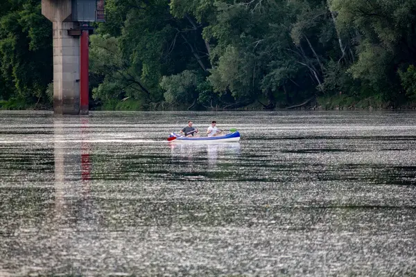 İnsanlar nehir boyunca bir teknede yelken açıyor.