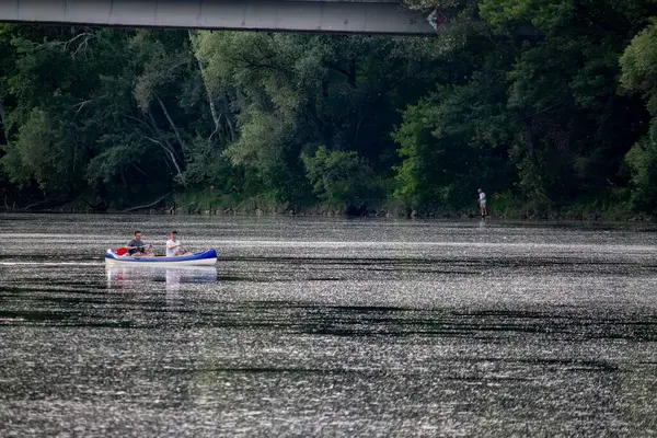 İnsanlar nehir boyunca bir teknede yelken açıyor.