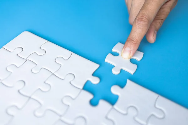 stock image White jigsaw in the hands, The correct solution. Teamwork, Solving and completing the task. Last piece of jigsaw puzzle. Assembling jigsaw puzzle pieces.