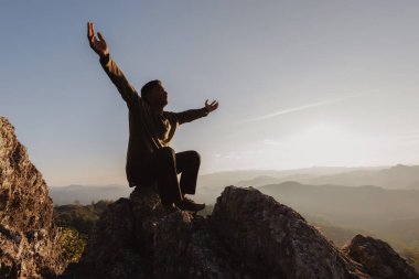 silhouette of man rise hand up praying  on top of mountain and sunset sky abstract background. Freedom and travel adventure concept. 