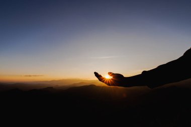 silhouette of man rise hand up praying  on top of mountain and sunset sky abstract background. Freedom and travel adventure concept. 