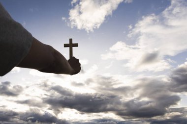 İnsan eli gökyüzünde bir haç tutuyor. Tanrı duasına olan inancın sembolü. Kurtuluş. Dua et. Hıristiyan konsepti.