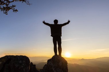 Silhouette of christian young man praying at sunrise, Freedom and travel adventure concept. Vintage tone filter effect color style.