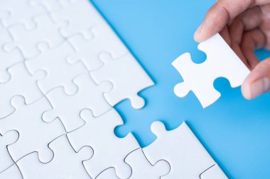 Ellerinde beyaz yapboz, doğru çözüm. Takım çalışması, çözme ve görevi tamamlama. Yapbozun son parçası. Yapboz parçaları monte ediliyor.