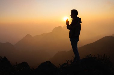 silhouette of a man is praying to god on the mountain. praying hands, pay respect.
